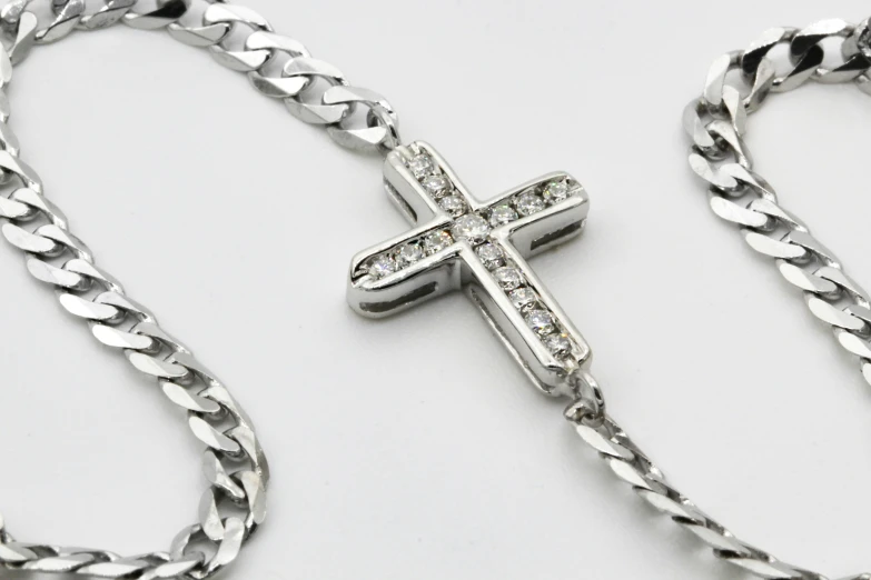 a silver cross and chain on a white surface