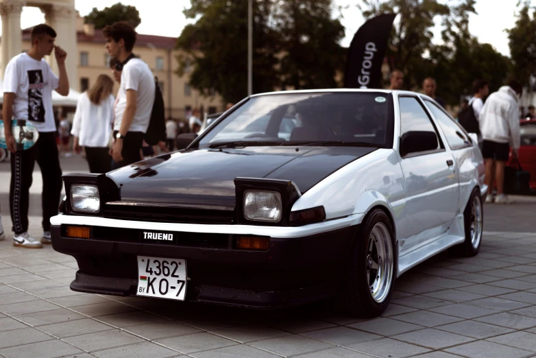 people looking at a very nice black and white car