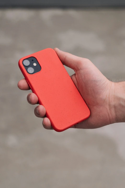 a hand holding an orange case for the iphone 12