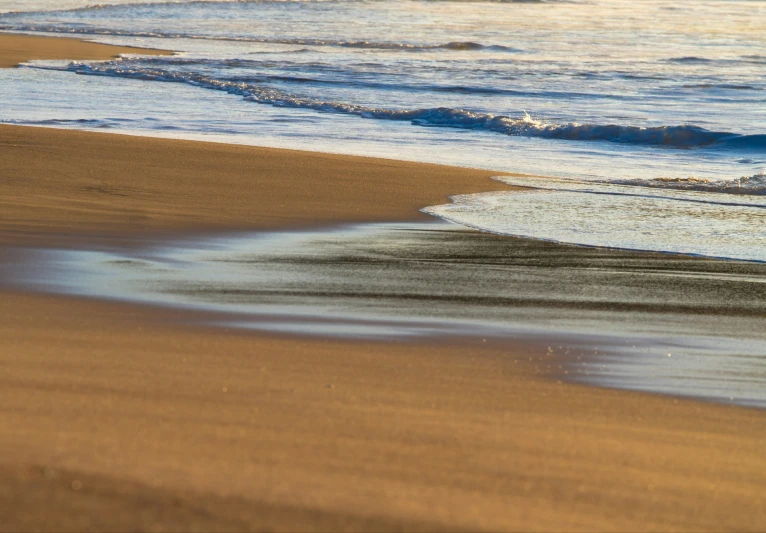 an ocean shore and waves crashing on sand