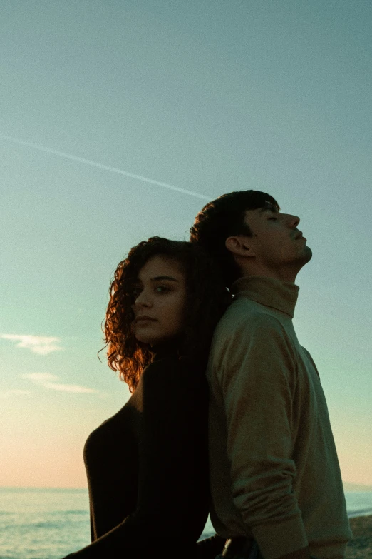 a couple standing by the ocean at sunset