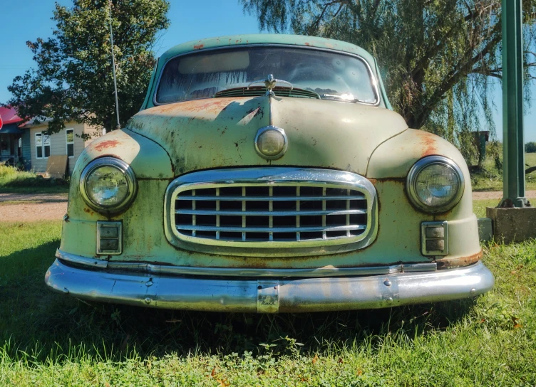 an old car is parked in a grassy area