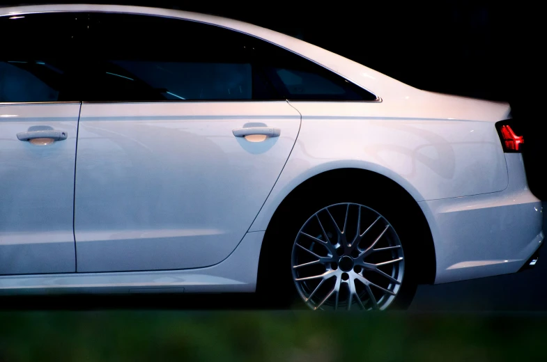 a white car is sitting on a dark surface