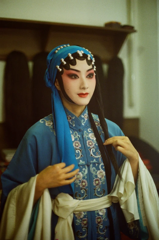 a woman in a blue outfit and shawl, holding soing