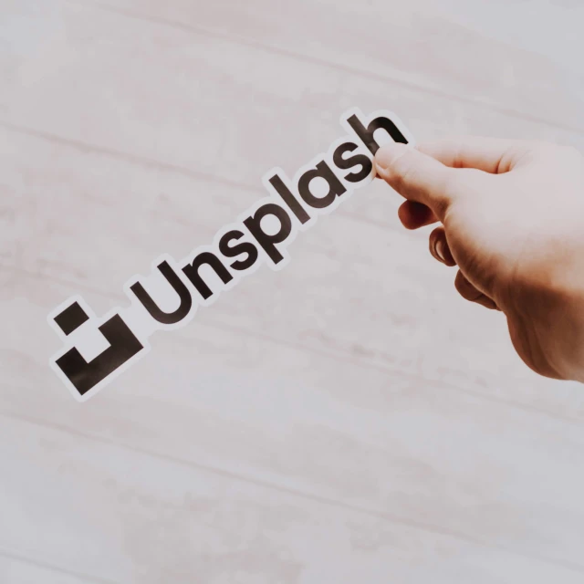 a person with their hand holding the word unplash