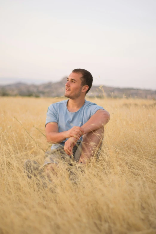 a man sitting in the grass outside in a field