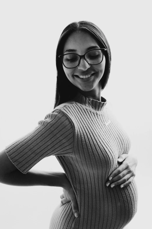 a smiling pregnant woman wears a sweater in a black and white po