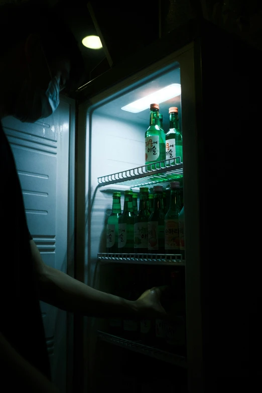 a person with their hand in an open refrigerator door