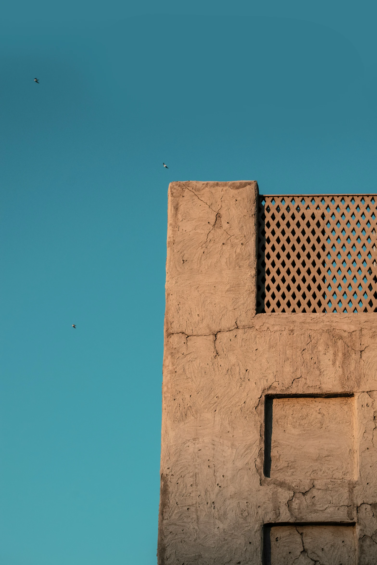 the side of an adobe building with a grate grill, taken from below