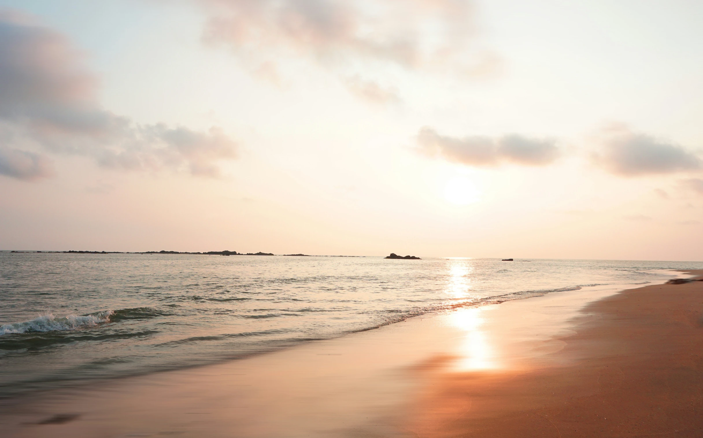 the sun setting on an ocean beach with calm waves