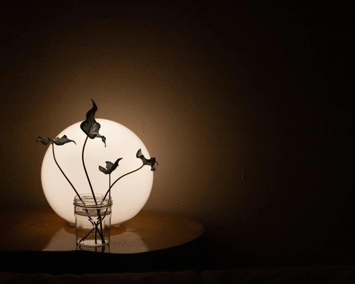 small vase with several tiny birds inside on a table