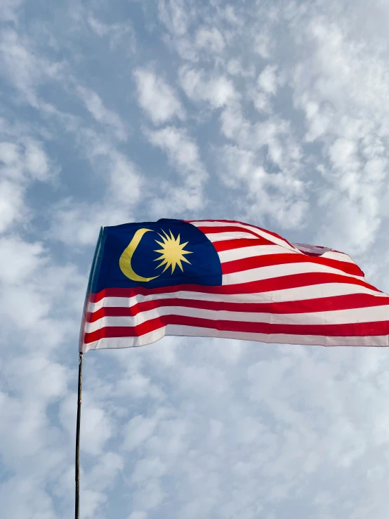 an american and malaysian flag on a pole