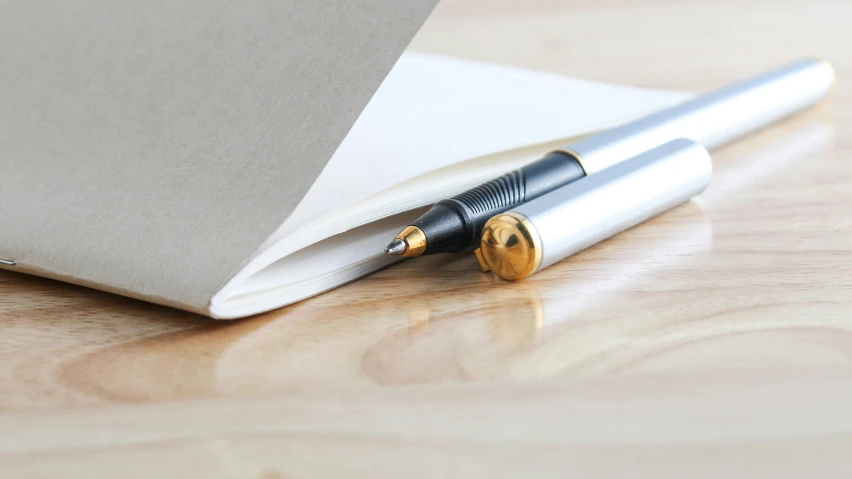 a pen is lying on the side of an opened notebook