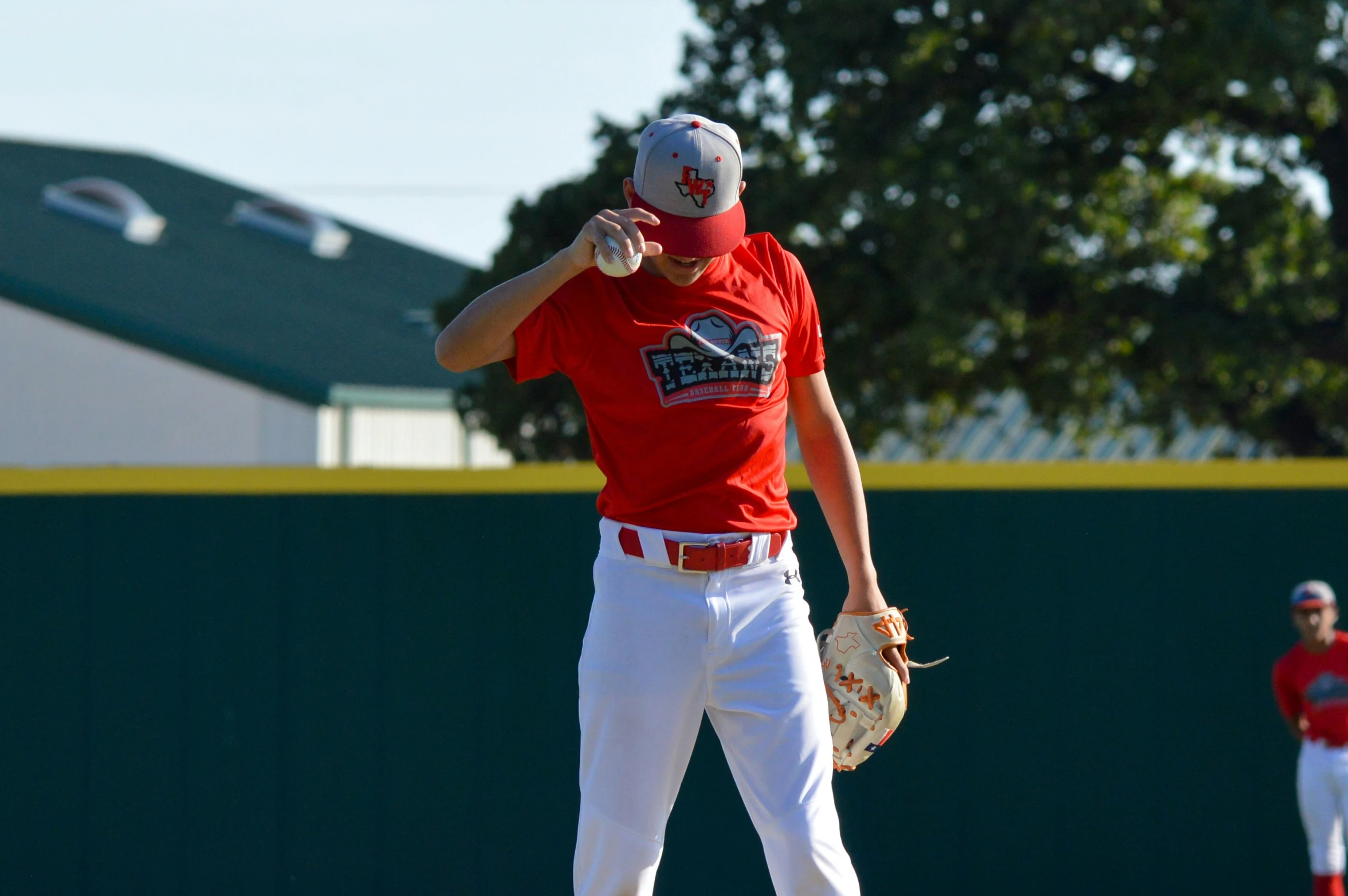 a man in a baseball uniform standing on a baseball field with his head tilted and throwing a baseball