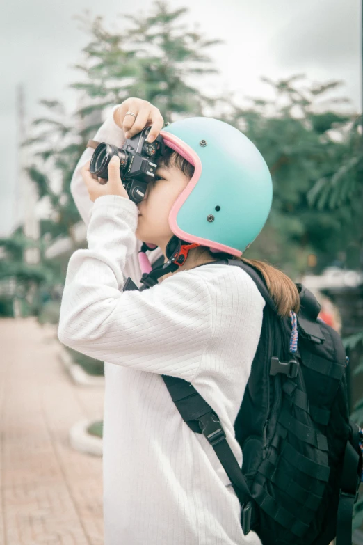 a girl with a helmet holding up a camera