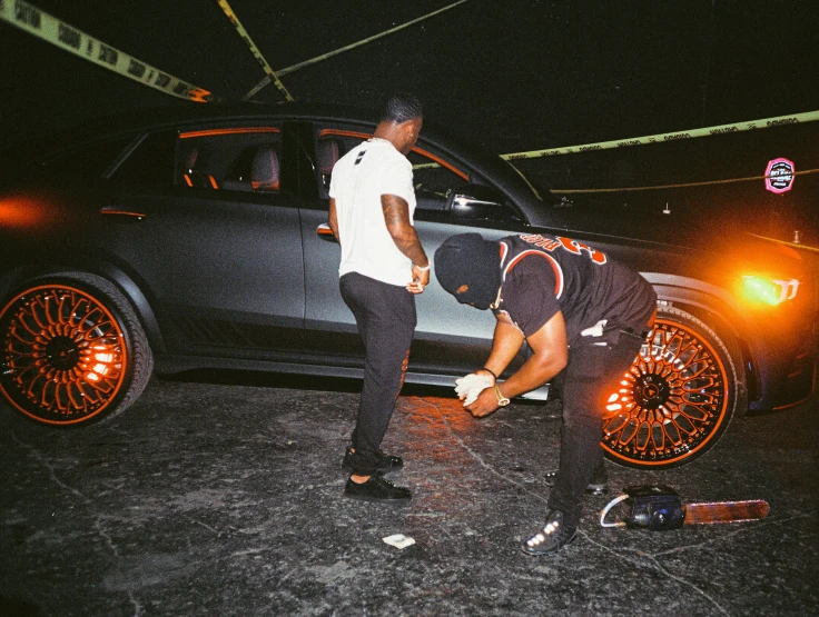 two men fixing the wheel on a car in the dark
