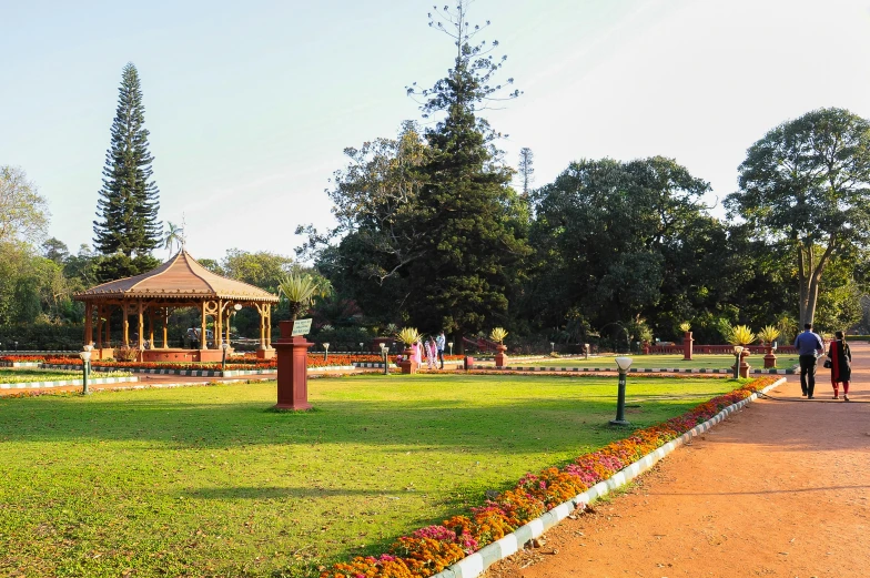 people walking in a park with green grass and a wooden bench