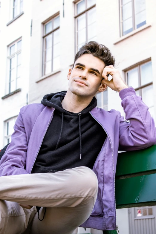 a man that is sitting on a bench with a cellphone