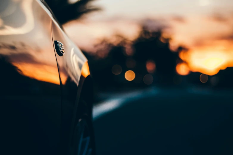 a view of the hood or side of a vehicle in front of the sunset