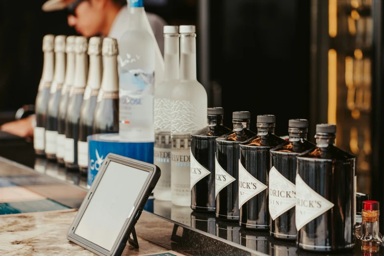 a man standing in front of bottles of liquor with a tablet on a bar