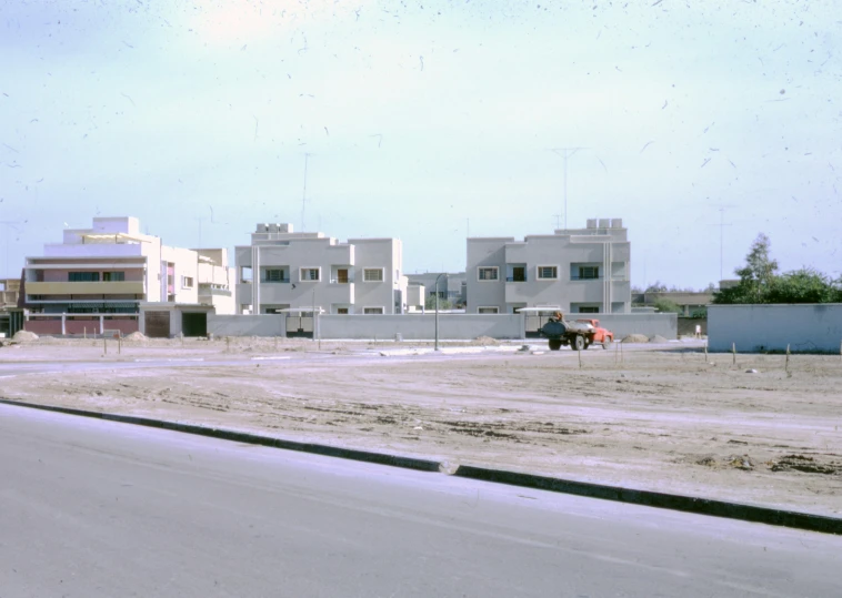 construction workers in a large empty lot in front of some buildings