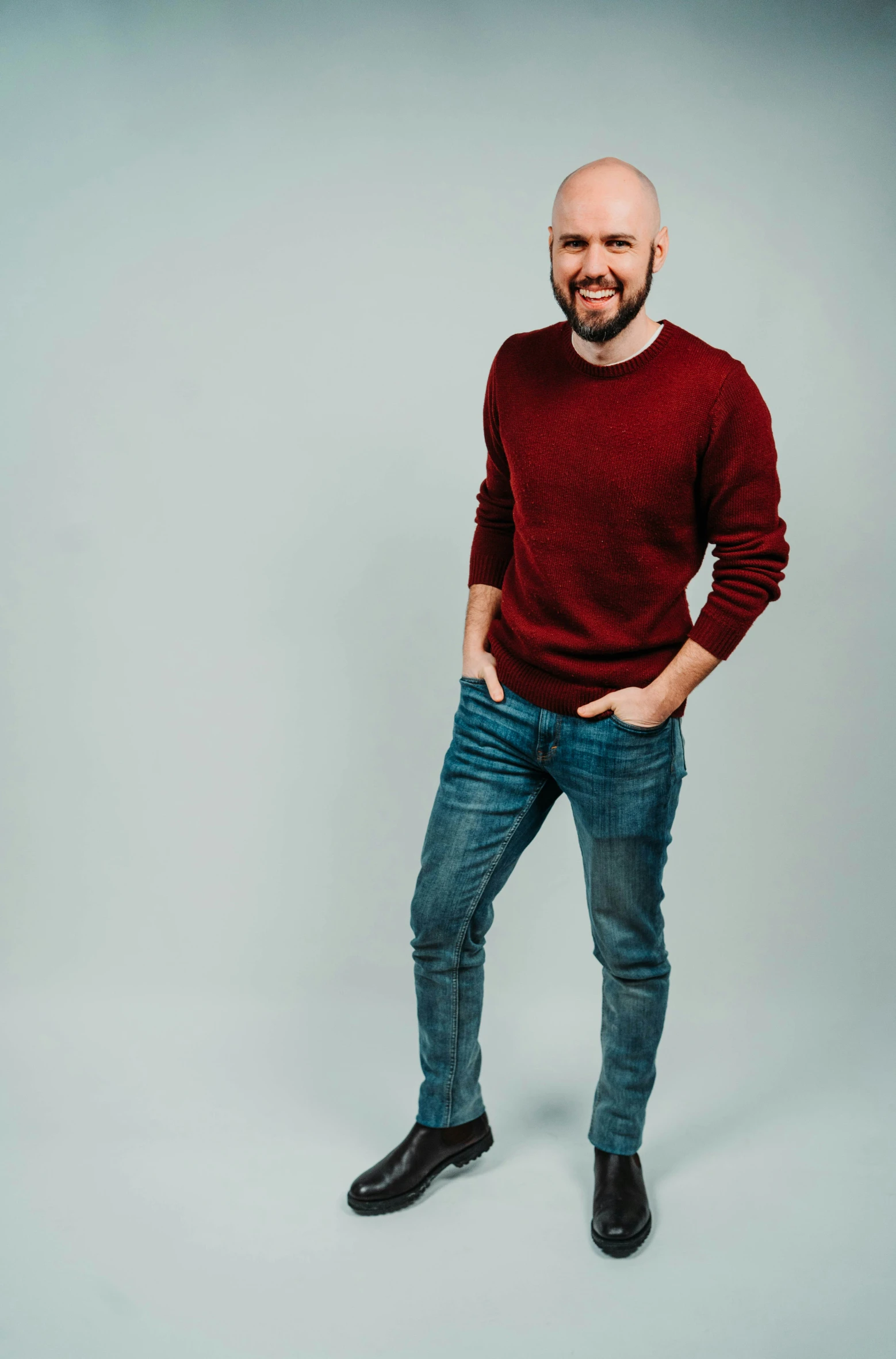 bald man posing for the camera with his hands in pockets