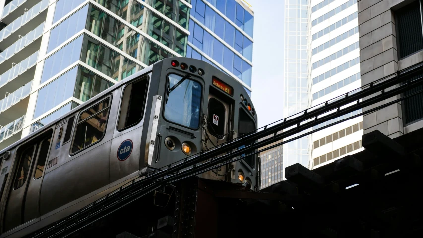 a passenger train driving through a city next to tall buildings