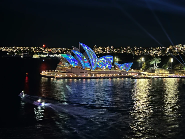 a boat sails near the opera at night