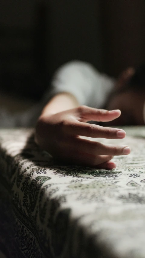 a person's hand on a bed with a blanket