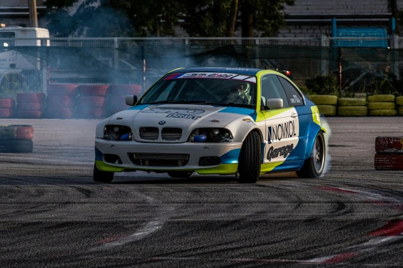 a car driving down a race track with smoke behind it