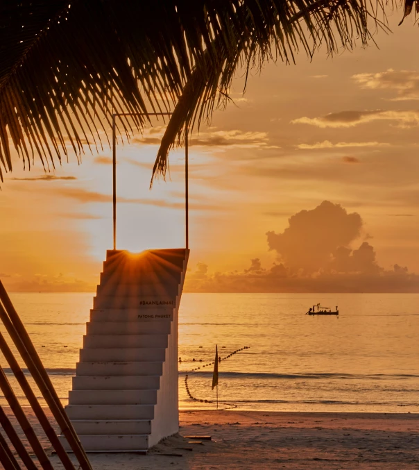 the sun setting on the water from behind some stairs