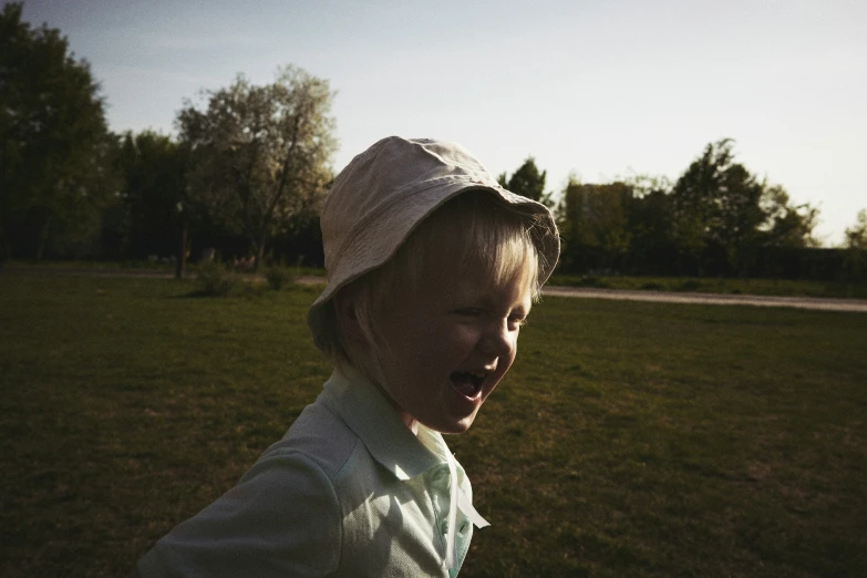 a child is looking away from the camera in a grassy area