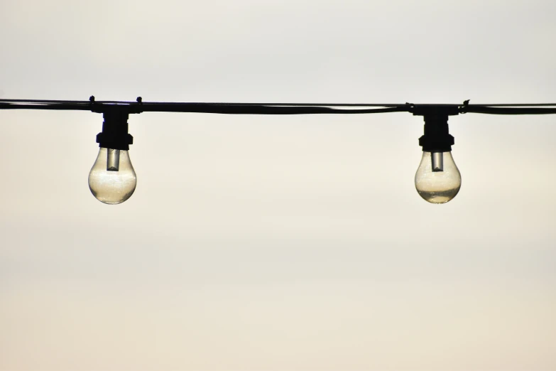 three light bulbs hang from the top of a metal pole