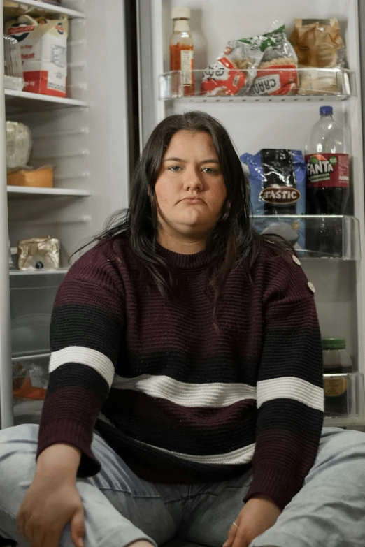 a person is sitting in front of an open fridge