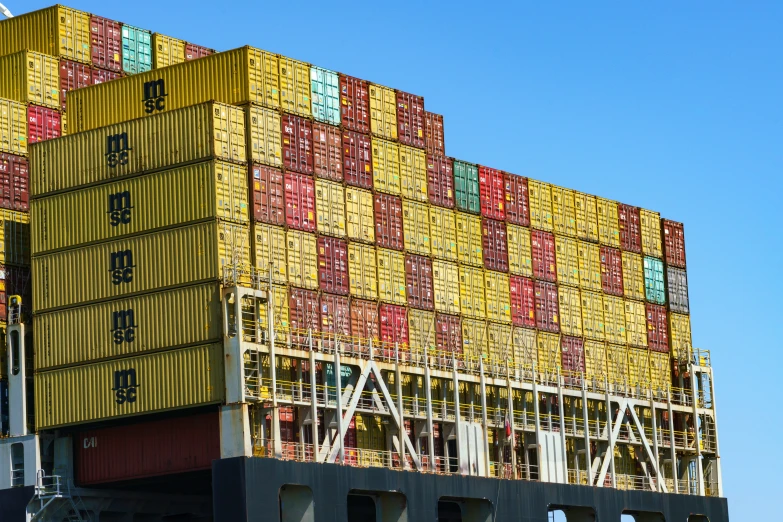 a large stack of yellow and red shipping containers sitting on top of a truck