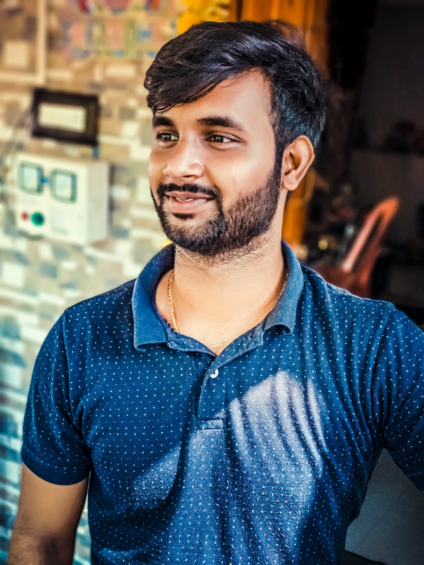 a young man with a beard standing in front of a wall