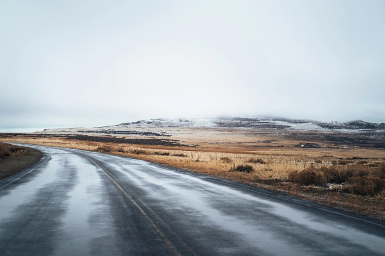 a snowy road with snow covered mountains in the distance