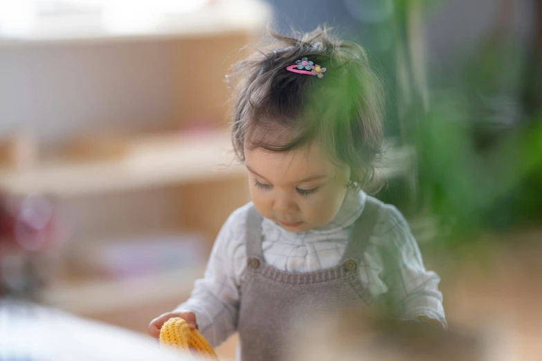 a little girl sitting down holding a yellow piece of food