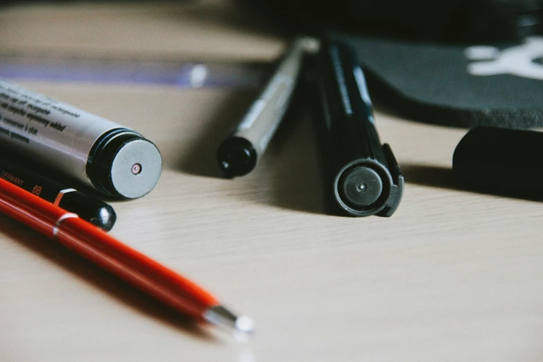 a pen, battery and pencil resting on a table