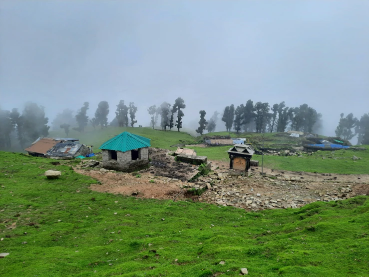 small, wooden huts in a field in a fog