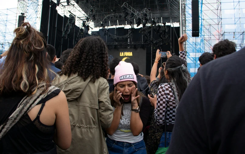 people standing around a concert with one talking on a phone