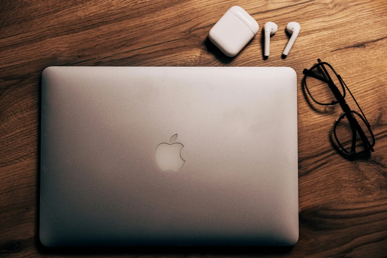 an apple laptop and some ear buds sitting on a table