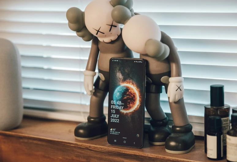 an electronic device is displayed on a shelf near a pair of stuffed animals