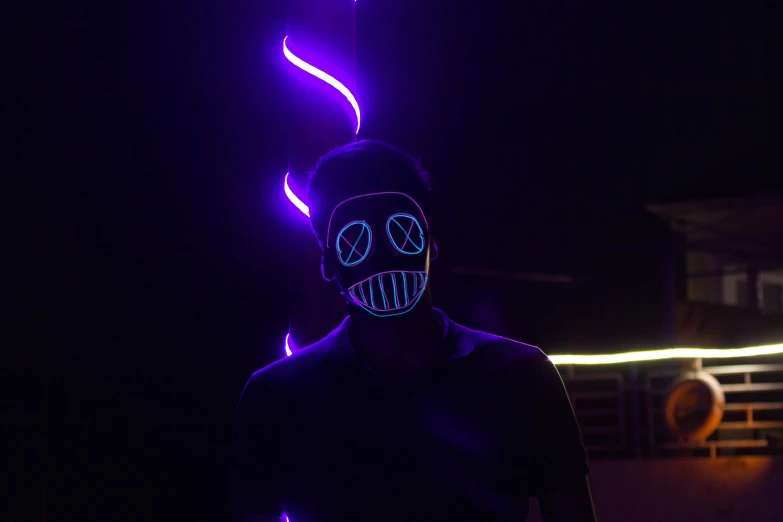 a man with neon painted face stands in front of a bright background