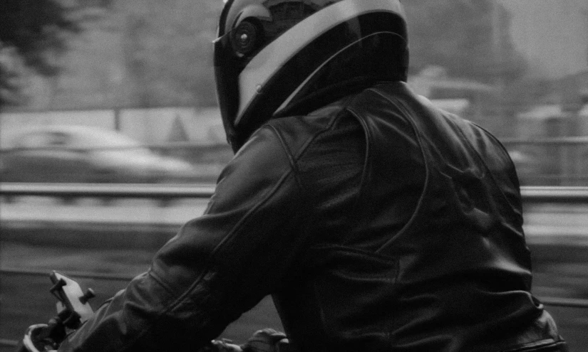a man in a hooded jacket riding his motorcycle