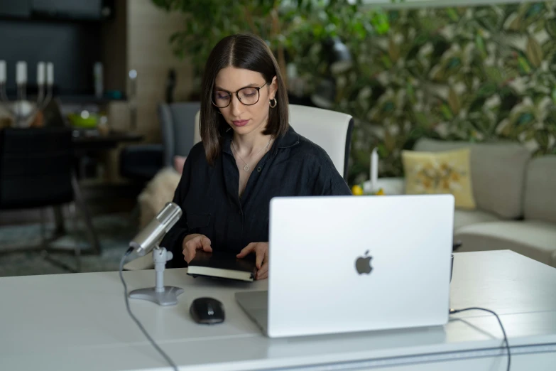a woman sitting in front of an apple laptop