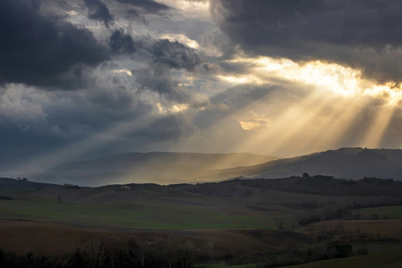 the sun breaks through storm clouds over green countryside