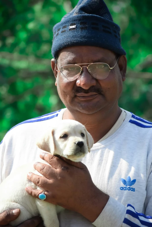 a man in sunglasses holding a dog while wearing glasses