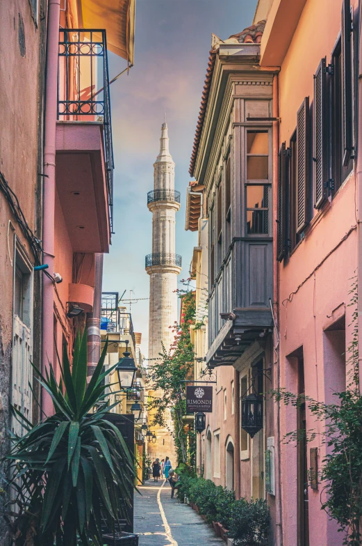 a narrow alley leading to an old white tower