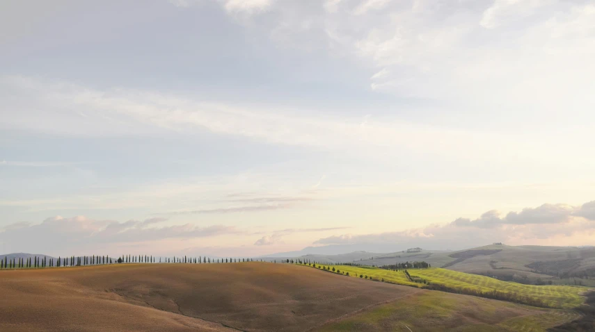 a brown field with grass and hills in the distance